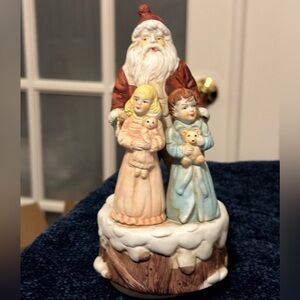 Beautiful Santa hugs 2 small children and plays Santa Claus is Coming to Town.